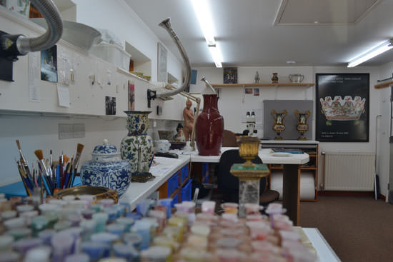 An artisan and artists studio with vases, fume extraction, paints. A colourful scene.